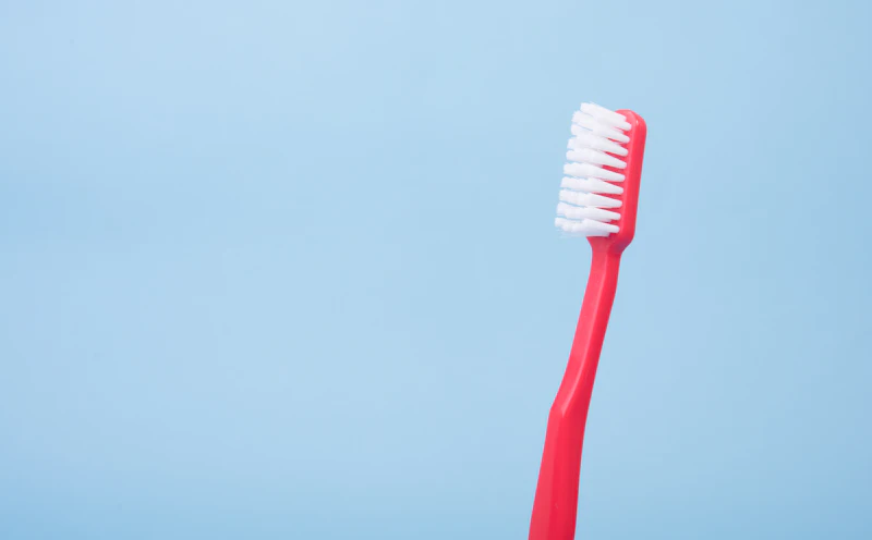 A red toothbrush against a pale blue wall